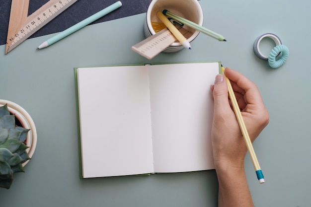 Mano de mujer lista para escribir en el cuaderno vacío