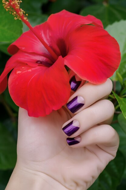 Mano de mujer con manicura púrpura brillo