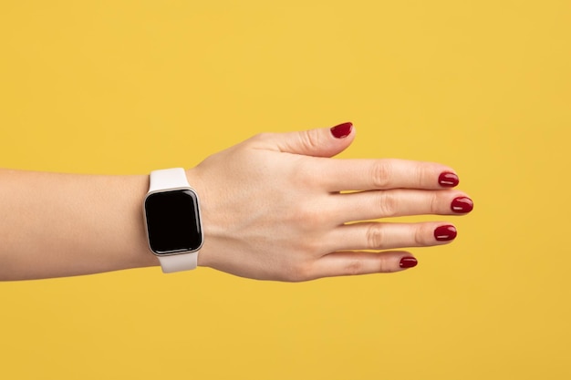 Mano de mujer con manicura roja y reloj inteligente con pantalla vacía y dispositivo de tecnología de correa blanca