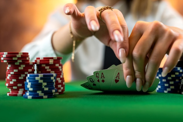 Mano de mujer en un montón de fichas de póquer en una mesa de póquer redonda apuestas arriesgadas en póquer aislado en un casino de fondo liso