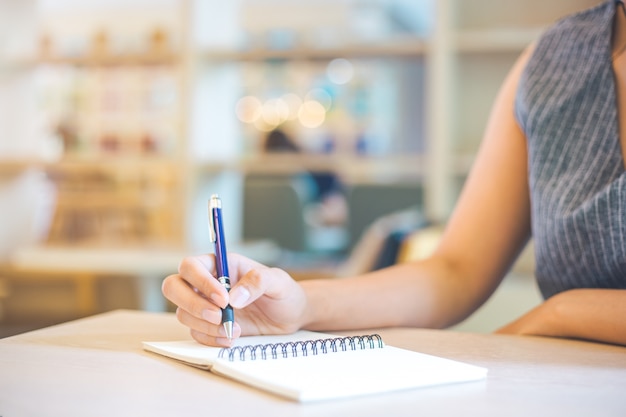 La mano de la mujer de negocios está escribiendo en libreta