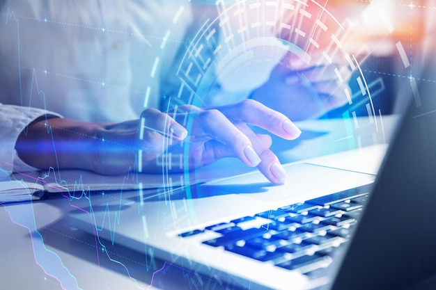 Mano de una mujer de negocios irreconocible que usa una laptop en la oficina con doble exposición de interfaz hud y gráficos. Concepto de alta tecnología. imagen tonificada