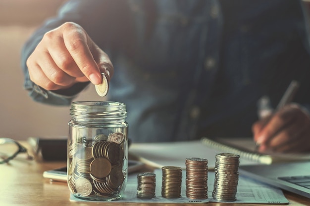 mano de mujer de negocios con monedas en vidrio.