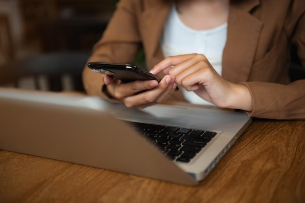 Mano de mujer de negocios que sostiene el dispositivo de teléfono inteligente en el café