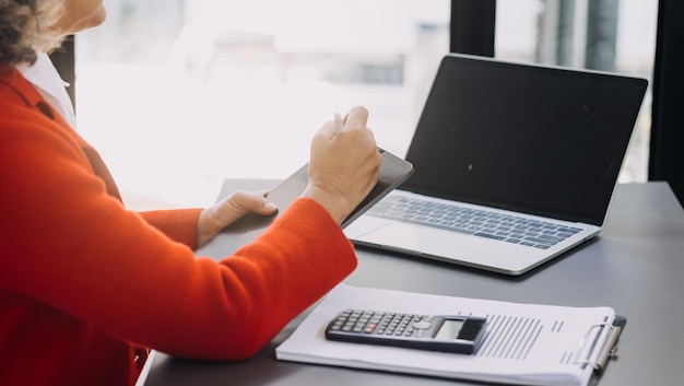 Mano de mujer de negocios trabajando con tableta de computadora portátil y teléfono inteligente en la oficina moderna con diagrama de icono virtual en la oficina moderna a la luz de la mañana