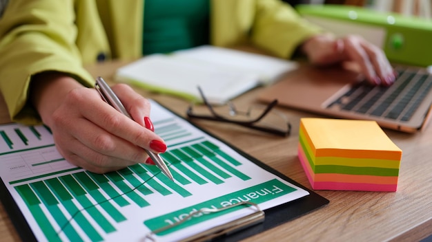 La mano de la mujer de negocios verifica la información en el informe financiero en las conductas del comercializador de gráficos