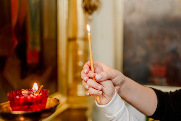 La mano de una mujer y un niño ponen una vela en la Iglesia