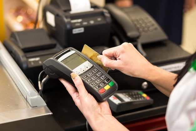 Mano de mujer con pase de tarjeta de crédito a través de terminal para la venta en el mercado Concepto de compras y venta minorista