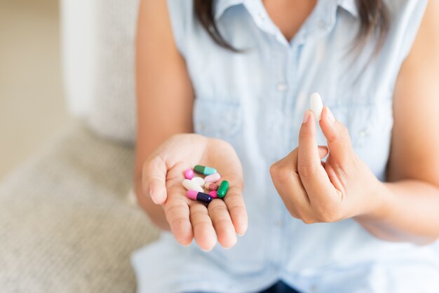 Mano de mujer con píldoras tabletas de medicina y cápsula en sus manos.