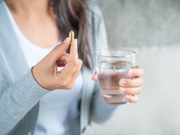 Foto mano de mujer con píldoras tabletas de medicina y vaso de agua