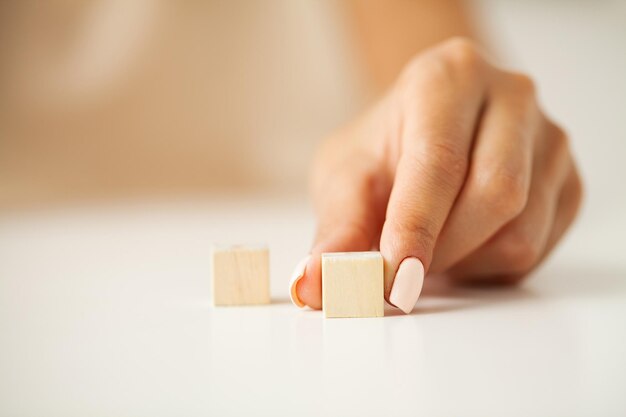 Mano de mujer poniendo y apilando cubos de madera en blanco en el escritorio con espacio de copia para la redacción de entrada