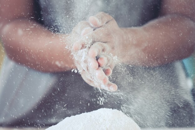 La mano de la mujer prepara la masa de pan que aplaude y que espolvorea la harina blanca en la pasta