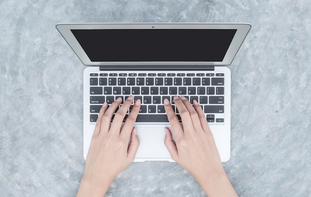 Mano de la mujer del primer que mecanografía en el teclado en el ordenador portátil