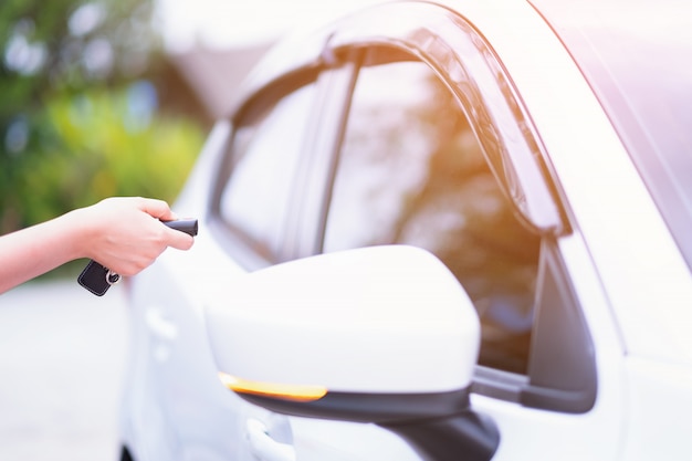 Mano de la mujer del primer que sostiene los sistemas de alarma de coche de control remoto