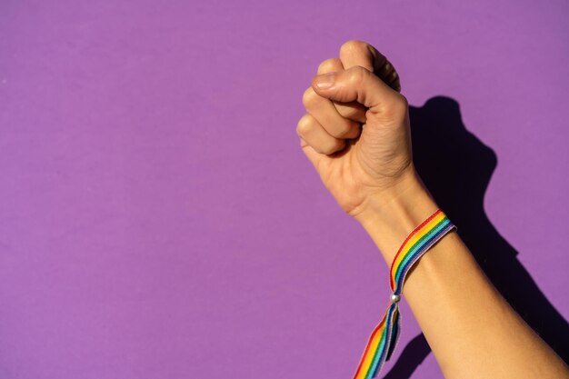 Foto mano de una mujer con el puño cerrado en el símbolo del feminismo a favor del feminismo fondo morado luchando a favor de las mujeres fuerza femenina bandera lgtb