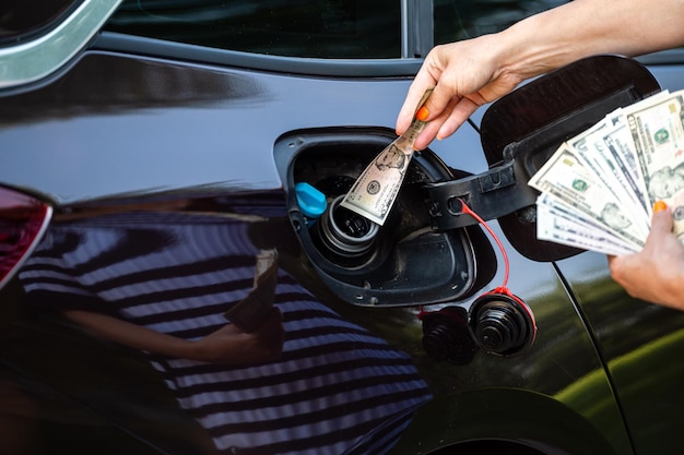 Mano de mujer que pone dinero en el tanque del automóvil concepto de cierre de crisis de combustible caro