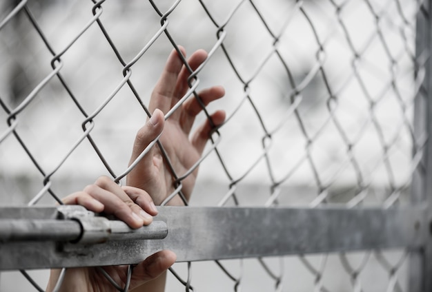 La mano de la mujer que sostiene la cerca del acoplamiento de cadena para recuerda concepto del día de los derechos humanos.