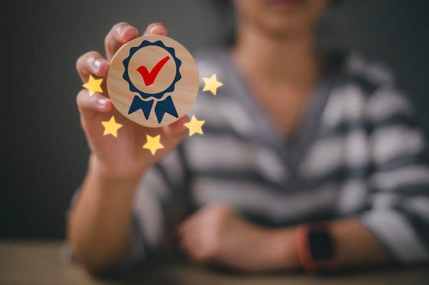 Foto la mano de la mujer que sostiene el signo del mejor servicio garantía de calidad 5 estrellas sobre un fondo de madera normas de garantía concepto de certificación y normalización iso