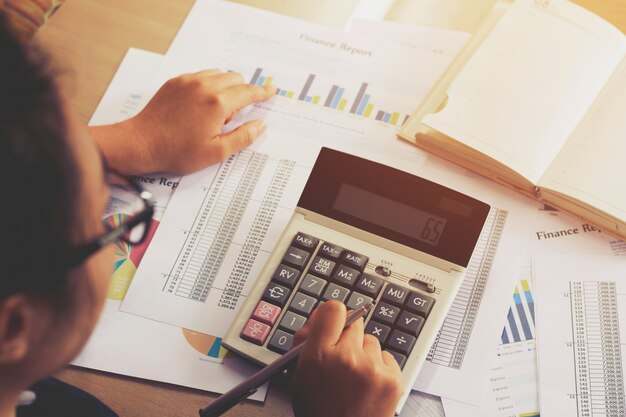 La mano de la mujer que usa la calculadora y la escritura hacen la nota con calcula