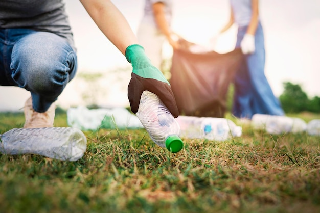 Mano de mujer recogiendo botellas de plástico de basura para limpiar en el parque