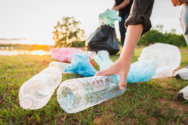 Mano de mujer recogiendo botellas de plástico de basura para limpiar en el parque