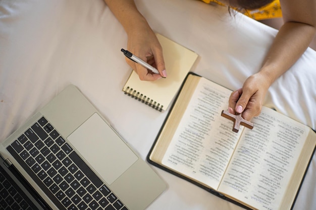 Mano de mujer rezando en la santa biblia por la mañana. Estudie la Biblia con la adoración en línea.