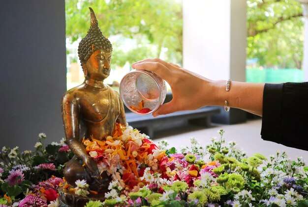 Mano de mujer rociar agua sobre una figura de Buda