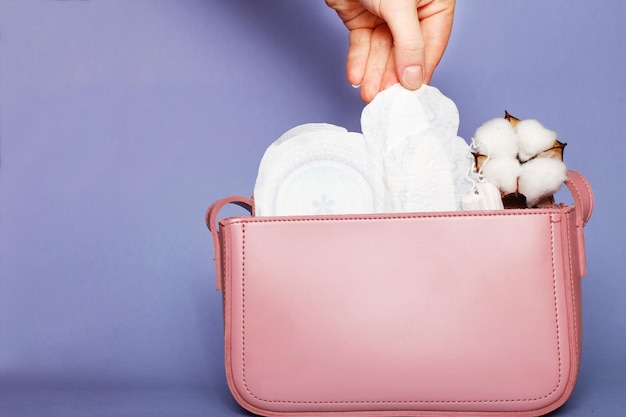 Mano de mujer saca panty liner de bolsa cosmética rosa con tampones y toallas sanitarias femeninas