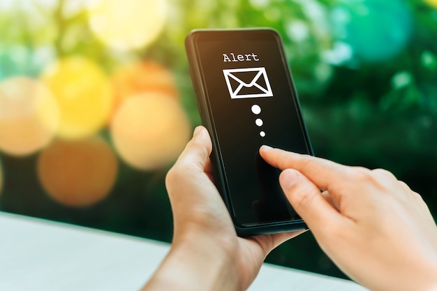 Foto mano de mujer con smartphone para enviar y recibir correo electrónico.