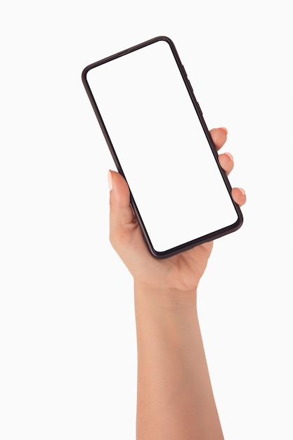 Foto mano de mujer con smartphone con pantalla en blanco sobre fondo blanco. mano de mujer sosteniendo la pantalla en blanco del teléfono inteligente negro con un moderno diseño sin marco, aislado sobre fondo blanco.