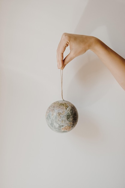 Mano de mujer sostenga un globo pequeño sobre fondo blanco Modelo mundial del planeta Tierra en las manos Salve la Tierra y el concepto de medio ambiente