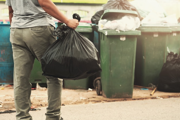 Mano de mujer sosteniendo basura en bolsa negra para limpiar en basura