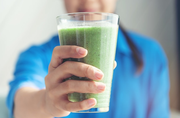 Mano de mujer sosteniendo un batido de jugo de vegetales