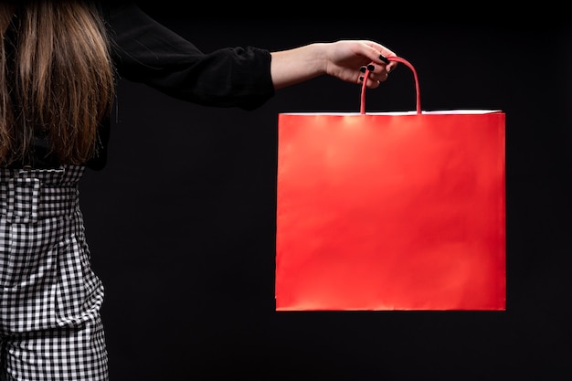 Mano de mujer sosteniendo bolsa de compras fondo negro