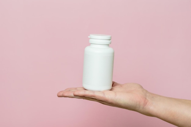 Mano de mujer sosteniendo una botella de píldoras o vitaminas Embalaje blanco para su píldora o cápsula y suplemento