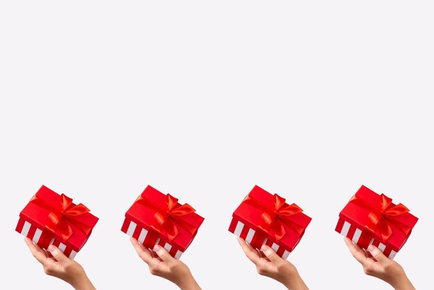 La mano de la mujer sosteniendo una caja de regalo a rayas con cinta roja sobre fondo blanco Navidad Año Nuevo Día de San Valentín y cumpleaños espacio de copia de concepto creativo