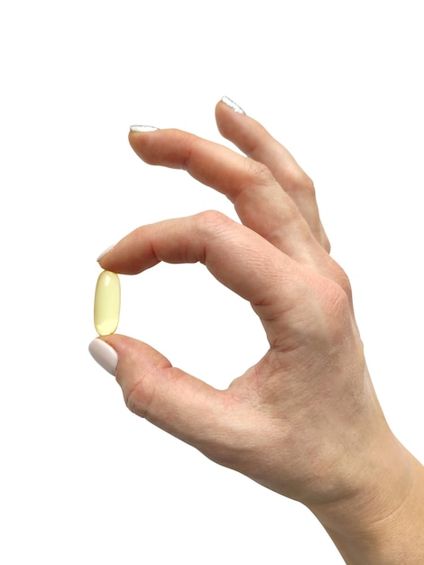 Mano de mujer sosteniendo una cápsula de aceite de grasa de pescado aislado sobre fondo blanco. Píldora de Omega 3 de primer plano. Concepto de medicina y farmacia. Dieta de alimentos saludables. Suplemento nutricional.