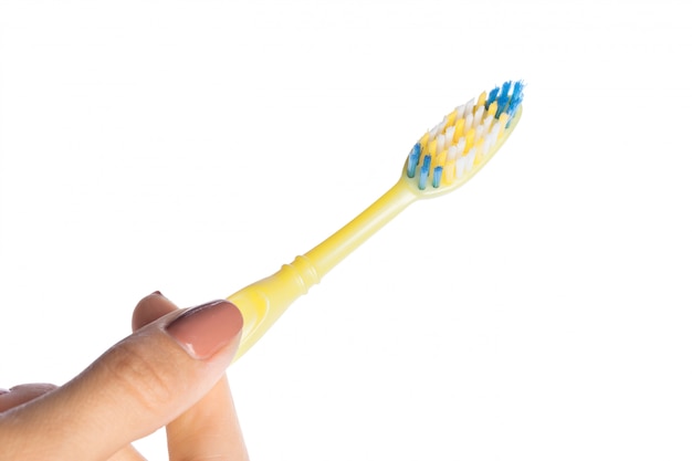 Mano de mujer sosteniendo un cepillo de dientes aislado en blanco