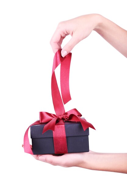 Mano de mujer sosteniendo la cinta y abriendo la caja de regalo aislada en blanco