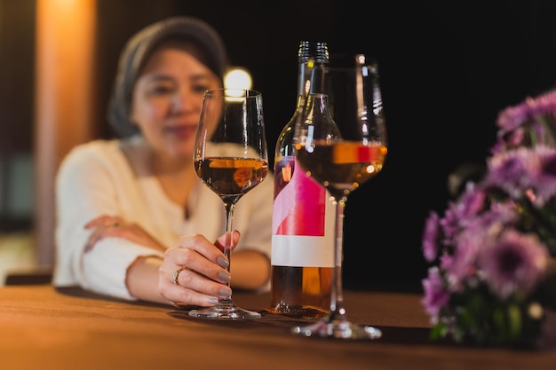 Mano de mujer sosteniendo una copa de vino en la mesa de la cena en el restaurante