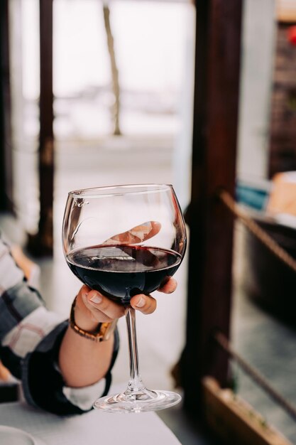 Mano de mujer sosteniendo una copa de vino con vino tinto