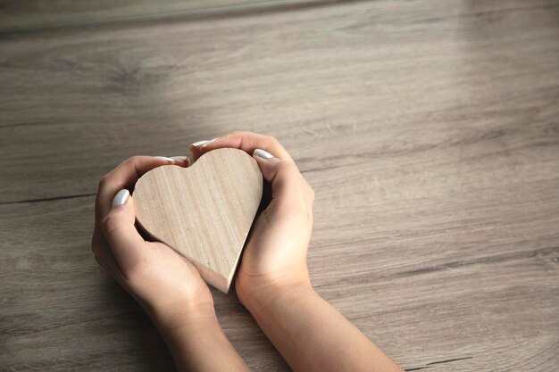 Mano de mujer sosteniendo corazón de madera