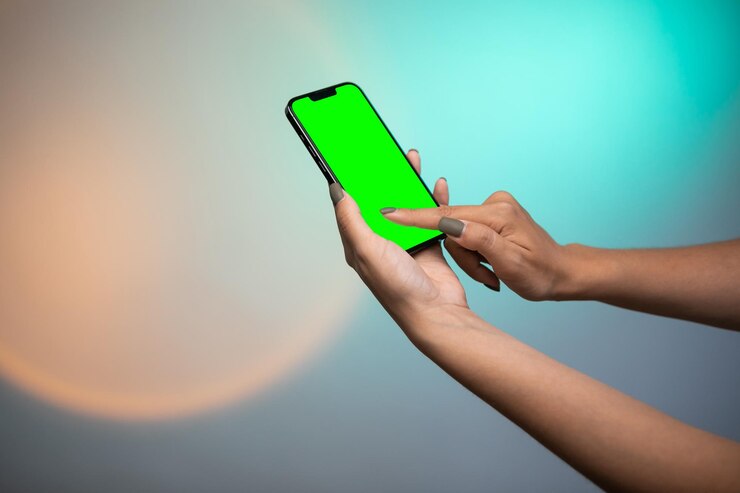 Mano de mujer sosteniendo un desplazamiento de Smartphone de pantalla verde y pantalla táctil sobre fondo colorido.