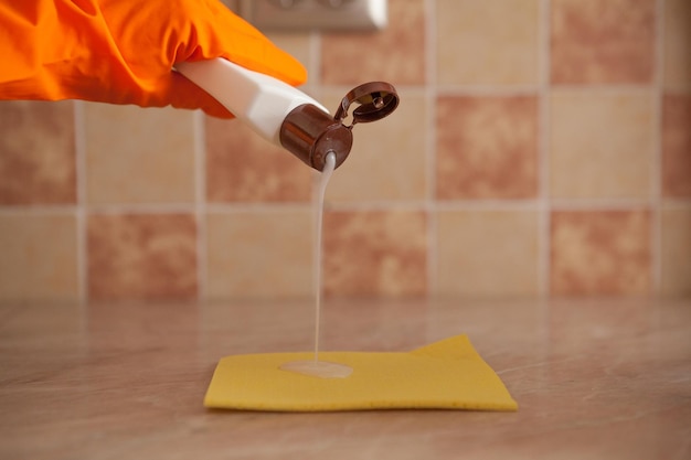 Mano de mujer sosteniendo una esponja amarilla y vertiendo líquido de limpieza en él concepto de limpieza e higiene