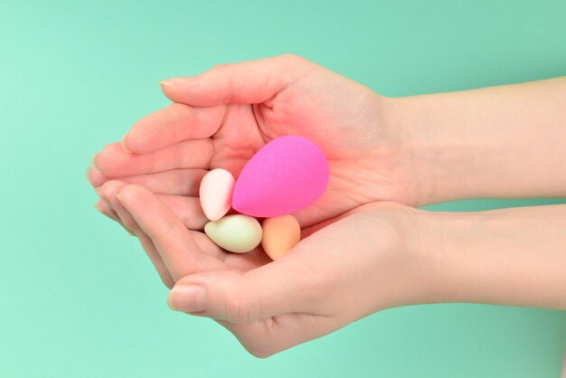 Mano de mujer sosteniendo esponja de belleza sobre fondo verde