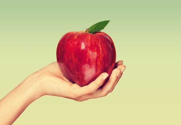 Mano de mujer sosteniendo gran manzana roja