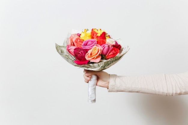 Mano de mujer sosteniendo un hermoso ramo de rosas de colores, diferentes flores rojas, amarillas, naranjas. Aislado sobre fondo blanco. Día de San Valentín o Día Internacional de la Mujer, concepto de vacaciones.