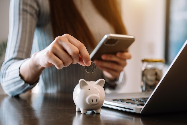 Mano de mujer sosteniendo moneda con hucha de cerdo Concepto de ahorro y cuentas financieras