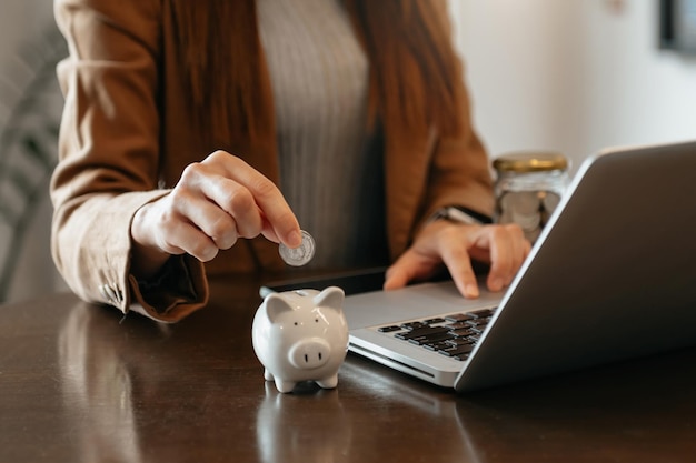 Mano de mujer sosteniendo moneda con hucha de cerdo Concepto de ahorro y cuentas financieras