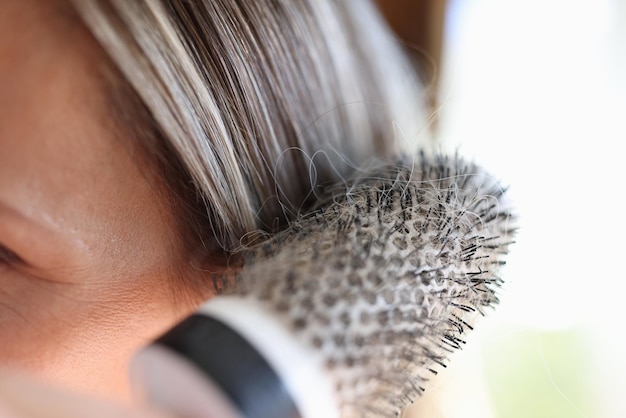 Mano de mujer sosteniendo un peine de cerámica lleno de cabello